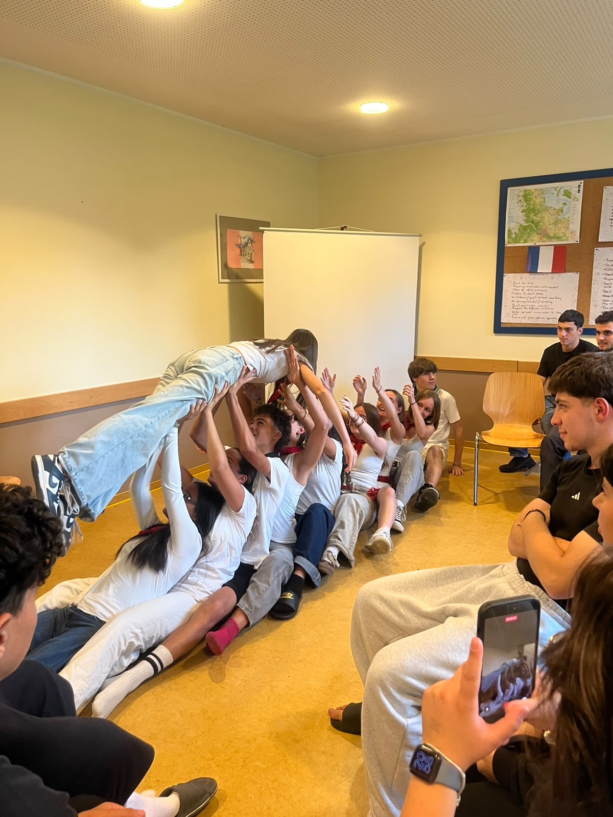 Jugendliche führen eine Team-Übung durch: Eine Person wird horizontal von mehreren getragen.